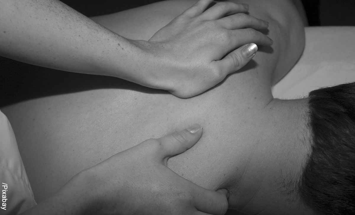 Foto de un hombre acostado boca abajo que revela los masajes en la espalda