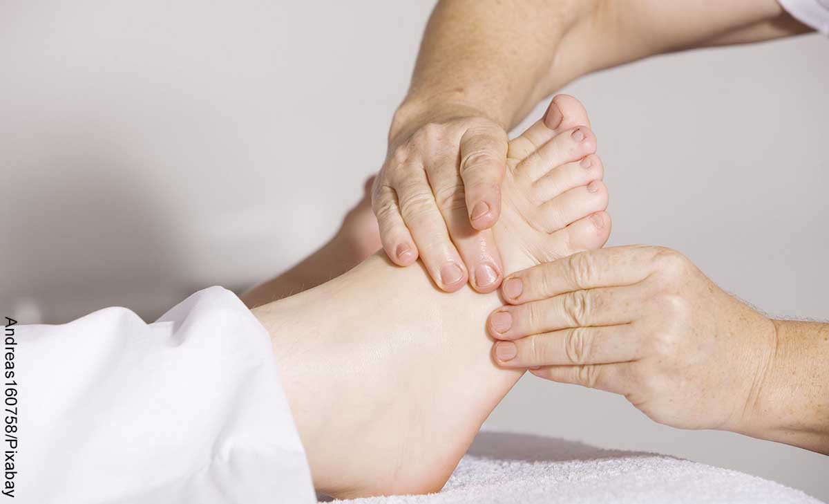 Foto de una persona tocando los pies a otra que revela los masajes en los pies