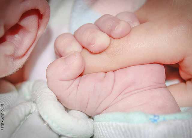 Foto de un bebé agarrando la mano de un adulto