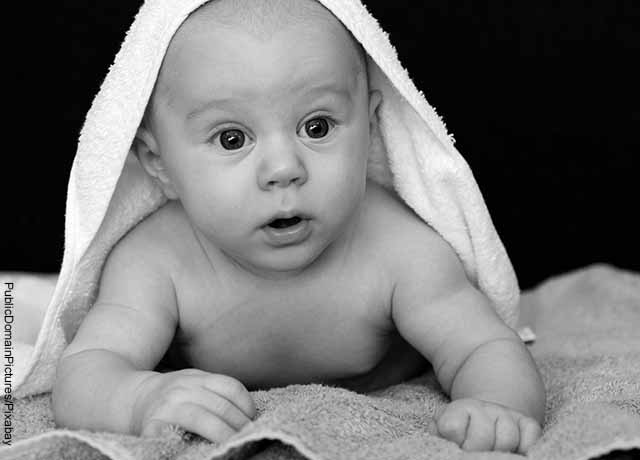 Foto de un bebé acostado con una cobija en la cabeza