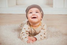 Foto de un bebé acostado en el piso sonriendo que muestra los masajes para bebés estreñidos