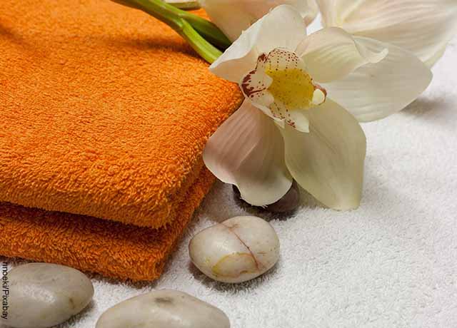 Foto de una toalla, flores y piedras de spa