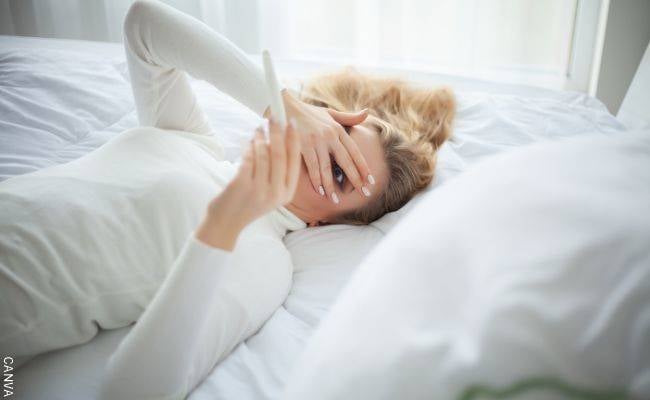 Foto de mujer en la cama esperando el resultado de un test para saber si está o no embarazada