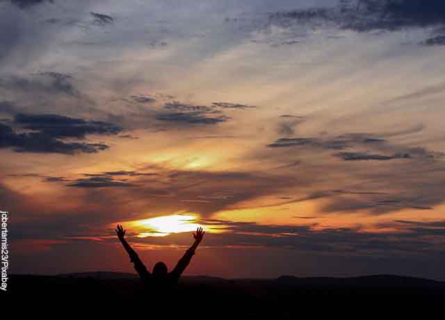 Foto de una persona levantando los brazos al cielo