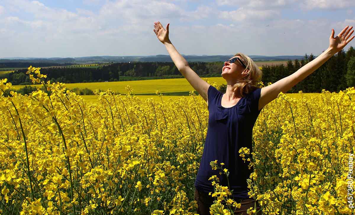 Foto de una mujer con los brazos abierto en el campo que muestra el ritual de agradecimiento