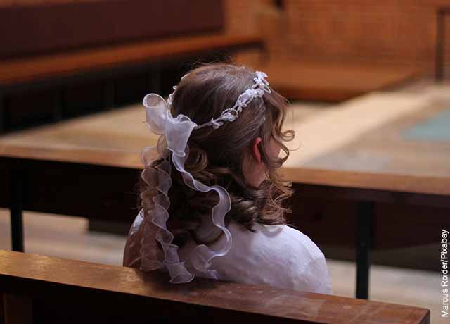 Foto de una niña vestida de blanco en la iglesia que muestra el ritual de la confirmación
