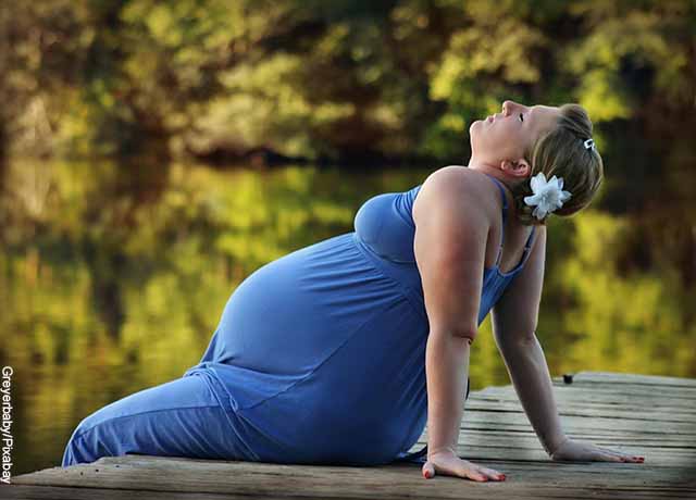 Foto de una mujer embarazada sentada en un muelle