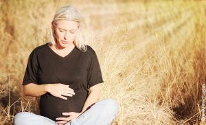 Foto de una mujer embaraza sentada en un campo que revela el ritual del día 40 después del parto