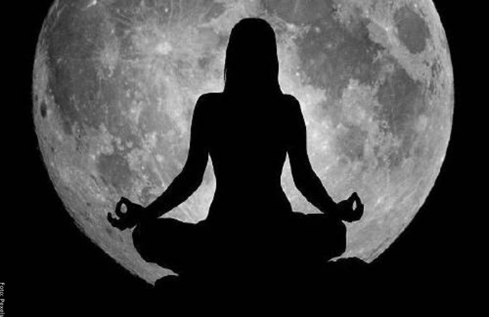Foto de mujer meditando con luna llena