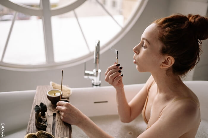 Mujer prendiendo un incienso en la bañera