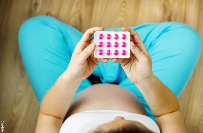 Foto cenital de una mujer embarazada con unas pastillas en las manos