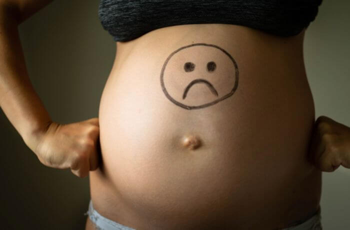 Foto de una barriga de embarazada con una carita triste dibujada