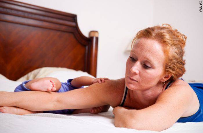 Foto de una mujer deprimida con su bebé en la cama