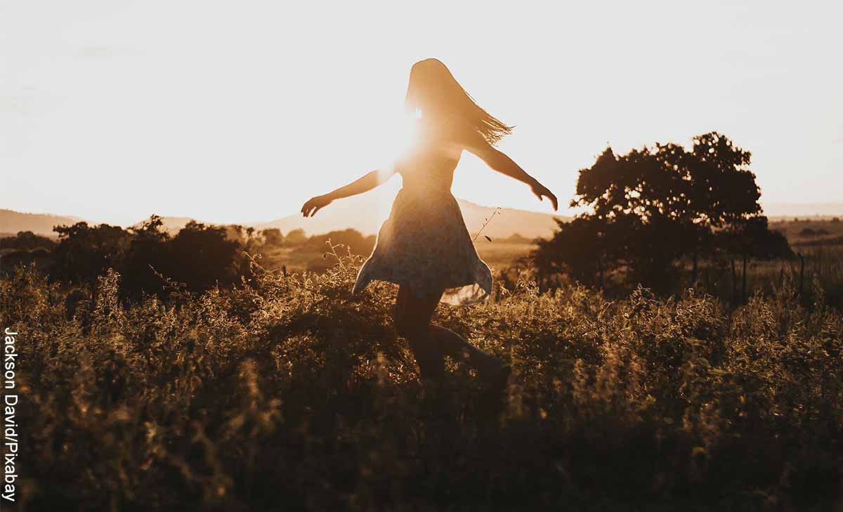 Foto de una mujer caminando por el prado que ilustra un mantra de agradcimiento