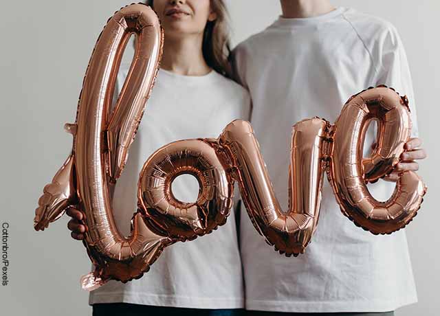 Foto de una pareja sosteniendo los globos con la palabra love que muestra el mantra de amor