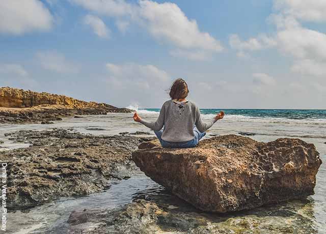 Foto de una persona sentada en una piedra meditando
