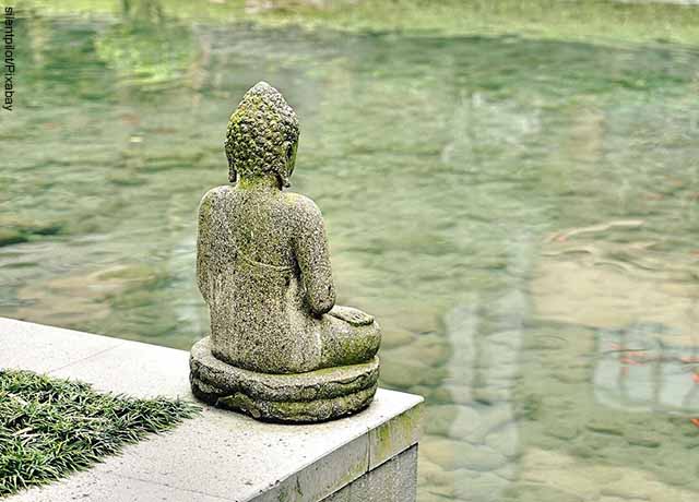 Foto de estatua de piedra frente a un lago que ilustra el mantra Om