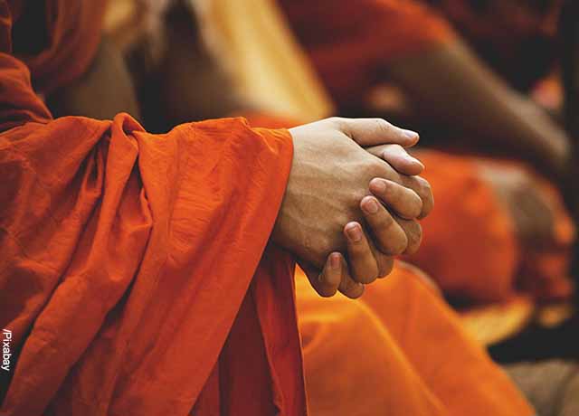 Foto de manos de monje budista en oración que muestra el mantra Om Mani Padme Hum