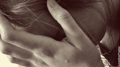 Foto de una mujer llorando tocándose la cabeza que revela los signos de alarma dolor abdominal