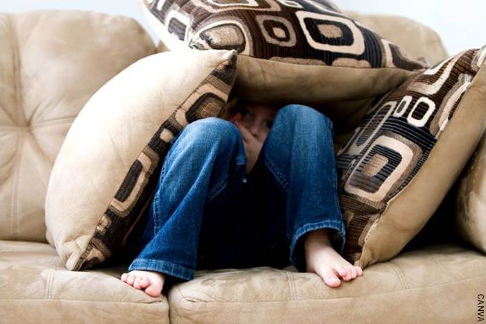 Foto de un niño escondido en los cojines de un sofá