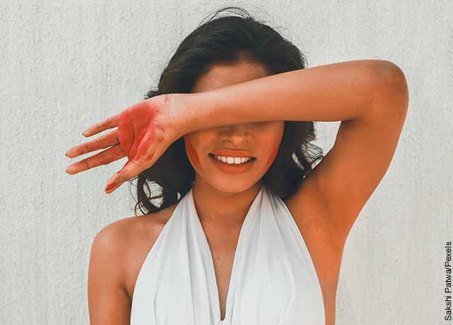 Foto de una mujer tapando su rostro con el brazo