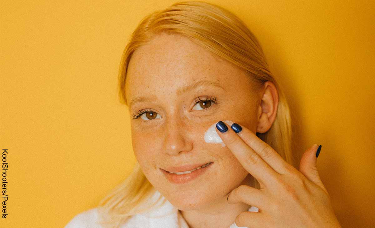 Foto de una joven aplicando crema en su rostro con los dedos de la mano