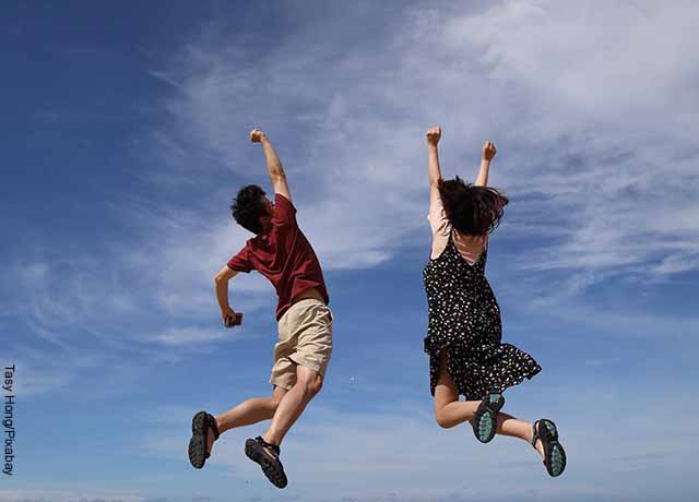 Foto de un hombre y una mujer saltando con los brazos arriba