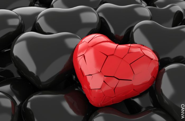 Ilustración de un corazón rojo roto entre corazones negros