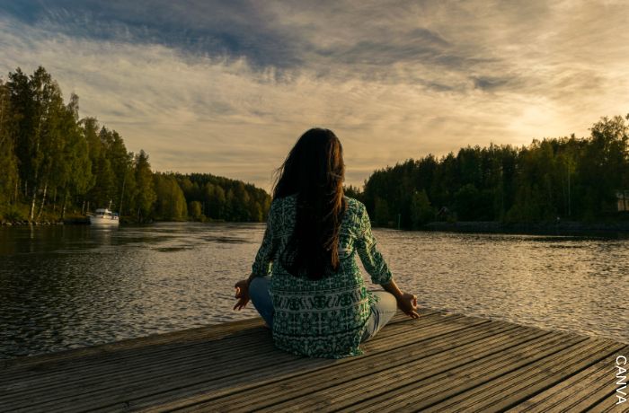 Foto de una mujer meditando frente a un río