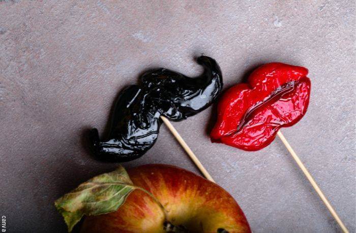 Foto de colombinas en forma de labios y bigote junto a una manzana