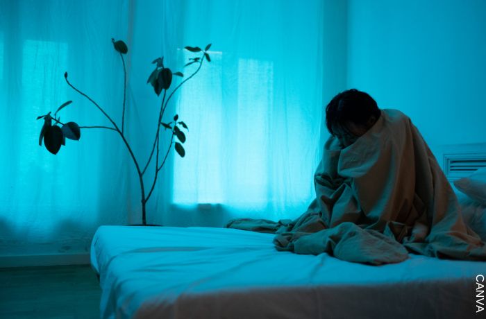 Foto de mujer enrolla en una cobija y sin poder dormir