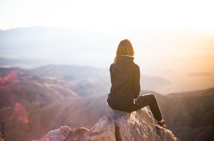 Foto de mujer sentada en la cima de una montaña
