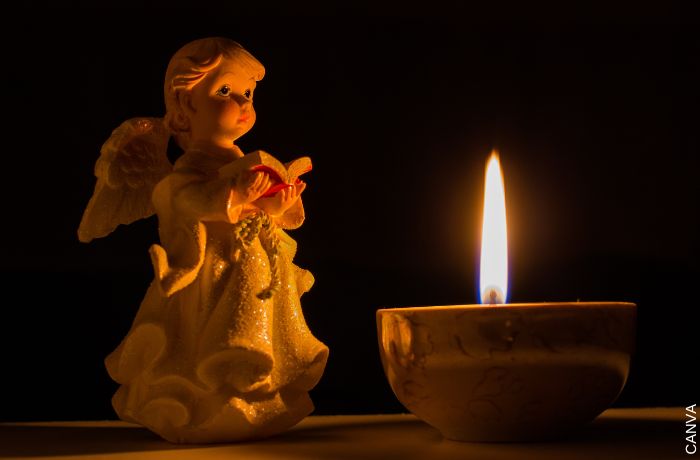 Foto de una estatua de un ángel con una vela en frente