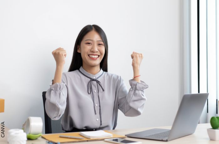 Foto de mujer celebrando frente a un computador