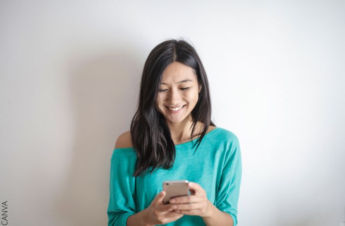 Foto de una mujer feliz usando su celular