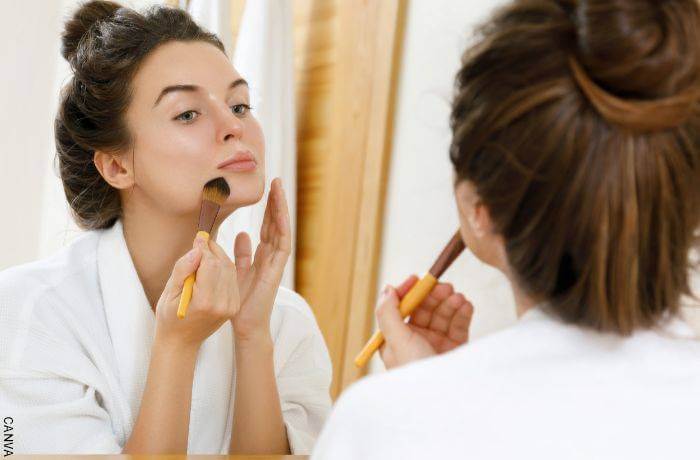 Foto de mujer maquillándose en el espejo