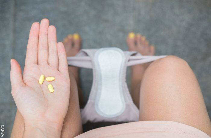 Foto de una chica sentada en el sanitario con pastillas en la man