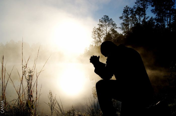 Foto de un hombre arrodillado en el monte rezando