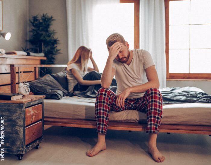 Foto de una pareja en pijama en distintos lados de la cama en medio de un disgusto