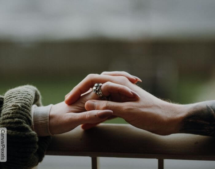 Foto de dos manos con los dedos entrelazados, una femenina y otra masculina, representando el signifiado de la hora espejo 11 11 en el amor