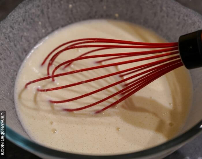 Foto de una mezcla en un recipiente con un batidor de mano para preparar una mascarilla de mayonesa para el cabello