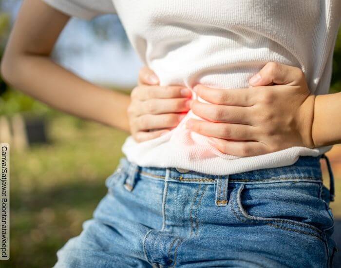 Foto de las manos de una mujer apretando su estómago a causa de la indigestión
