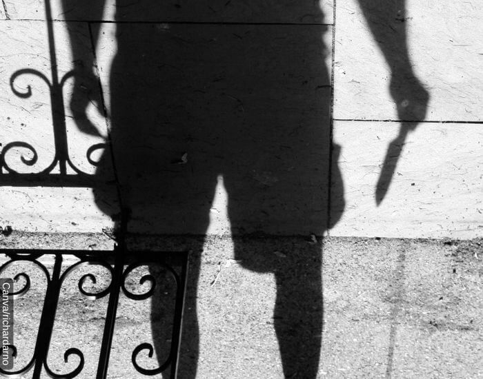 Foto de la sombra de un hombre en pantaloneta con un cuchillo en su mano