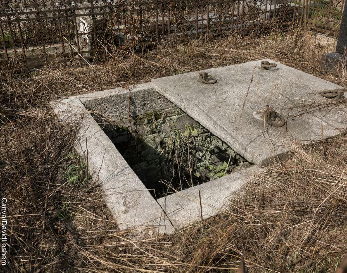 Foto de una tumba abierta con una tapa de cemento pesada y vieja