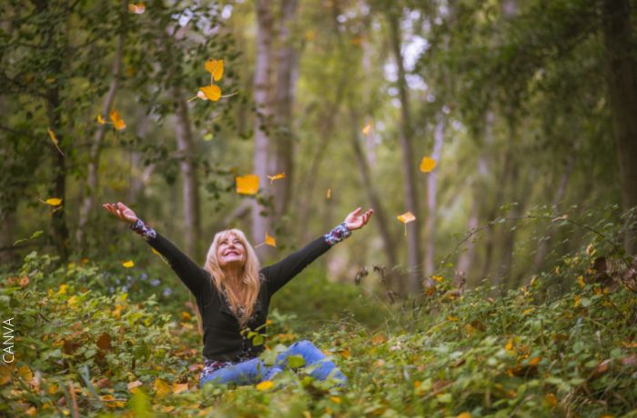 Foto de una mujer feliz sentada en el bosque