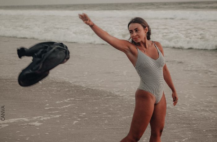 Foto de mujer en la playa tirando una prenda