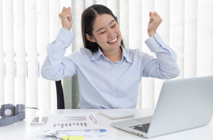 Foto de una mujer feliz frente a un computador