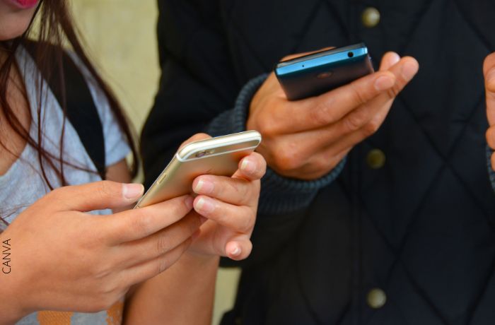 Foto de dos personas con sus celulares en la mano