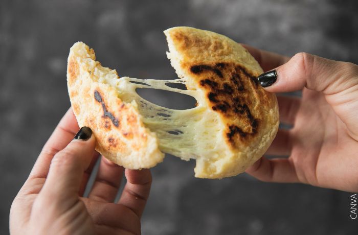 Foto de una arepa partida a la mitad con el queso estirado en la mitad