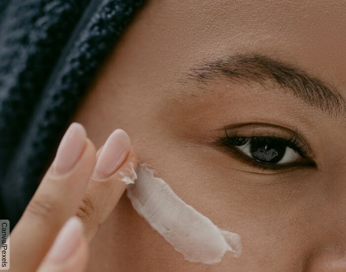 Foto de una parte del rostro de una mujer aplicando crema sobre su pómulo